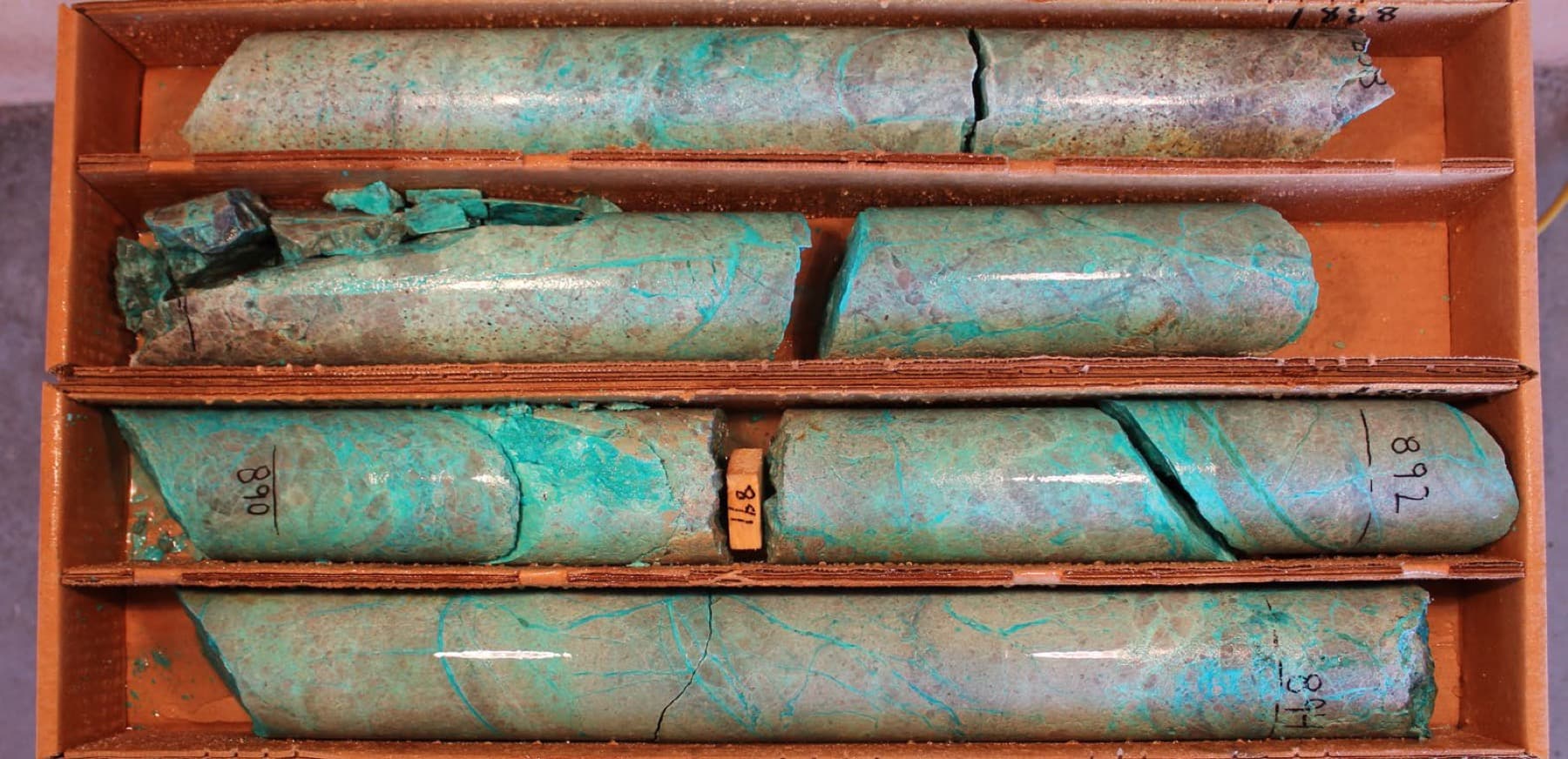 Drill core trays showing vivid green malachite and chrysocolla copper mineralization